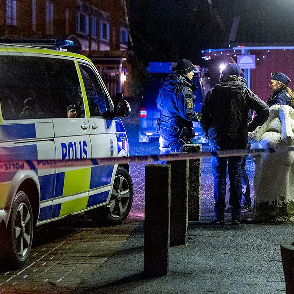 Poliser och kriminaltekniker vid en avspärrad brottsplats i ett bostadsområde på kvällen, bredvid en parkerad polisbil. Bild från Södertälje där Salwan Momika blev skjuten till döds.