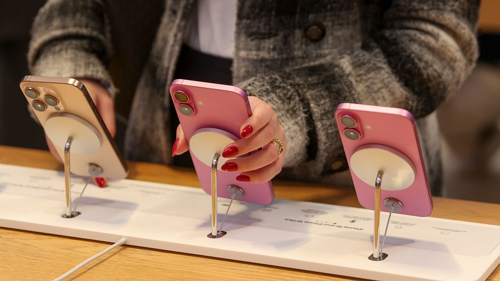 Person testar smartphones på utställningsställ.